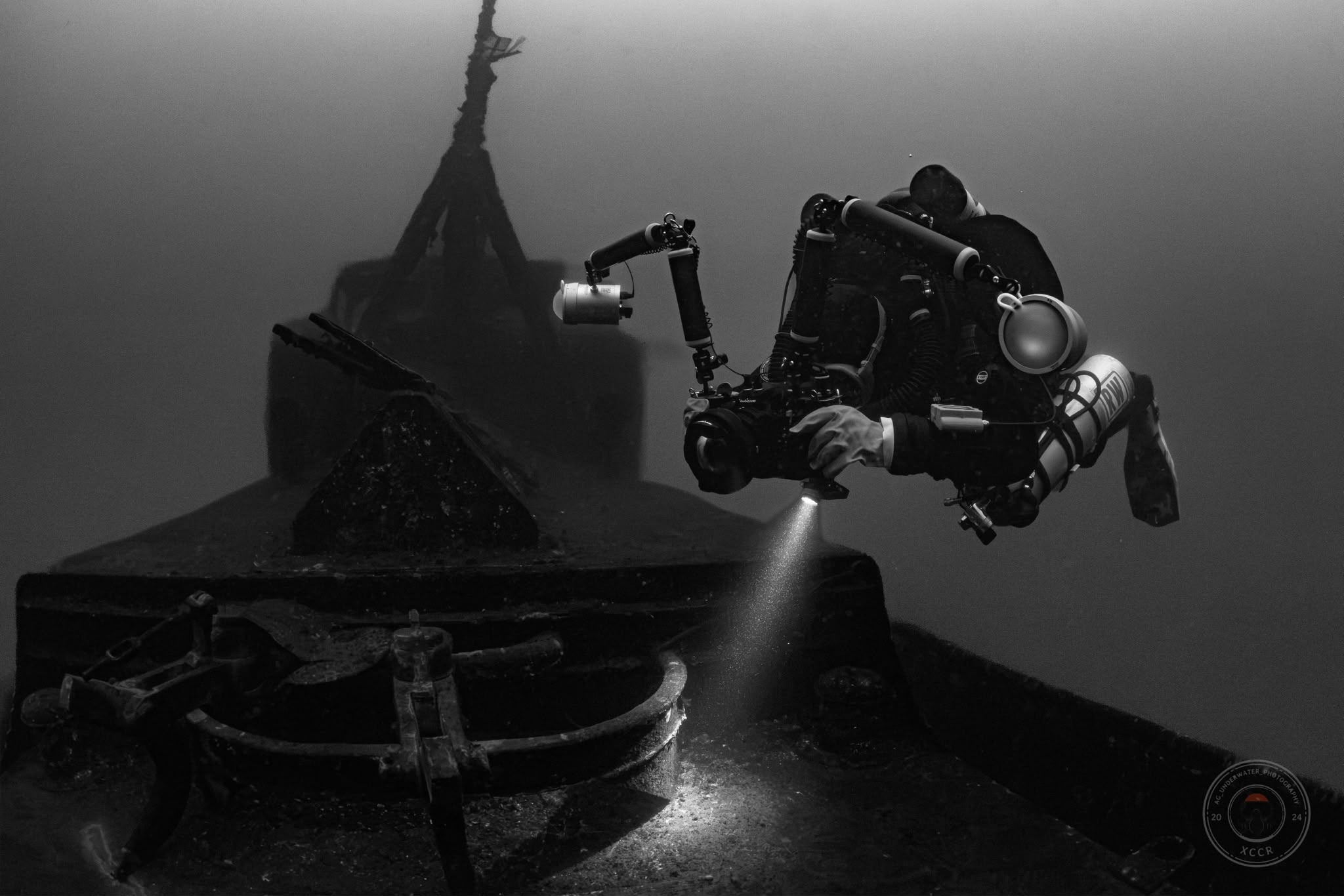 Richard diving over a wreck with his camera rig and strobes, in black and white