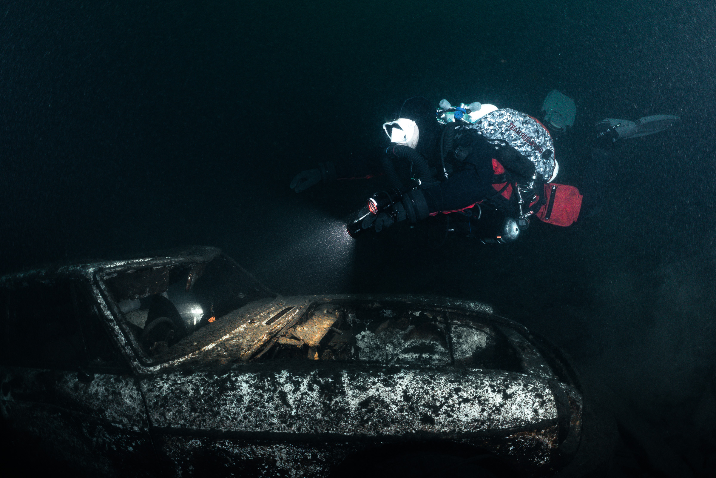 Torch beam lighting a sunken car wreck, Stoney Cove, 20 m
